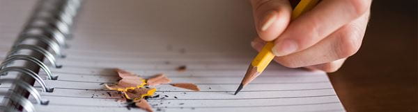 Photo of someone writing with a pencil and note pad
