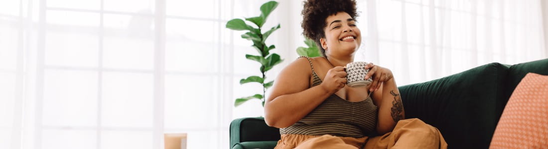 smiling-woman-sitting-on-sofa-having-coffee